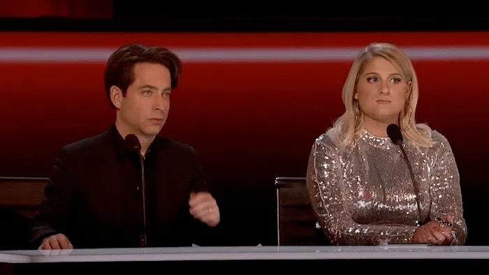 Two judges listening at a red-lit desk