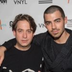 Two men posing with arms around each other at a music event