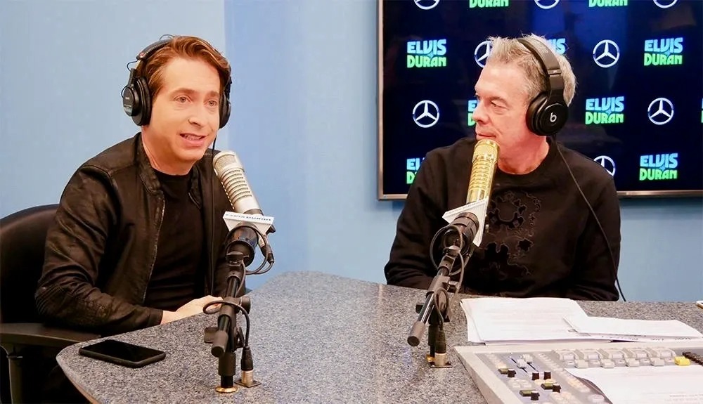 Two men in headphones at a radio studio microphone