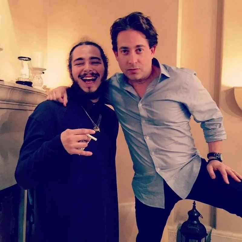 Two men posing together in a softly lit room