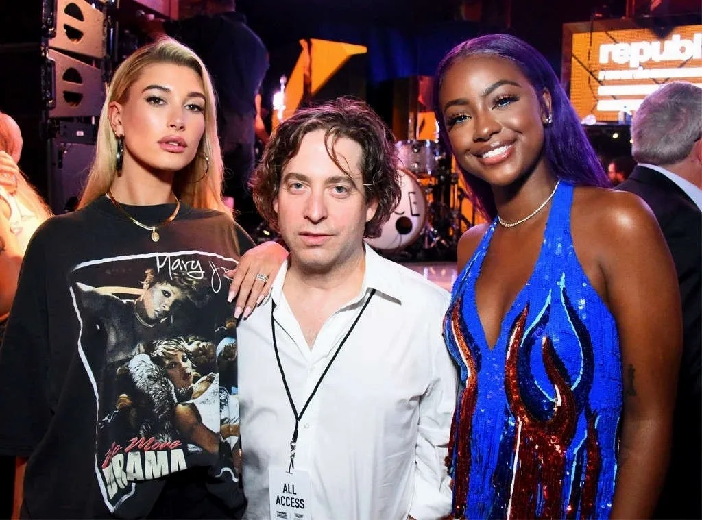Man in a lanyard posing between two women at a concert