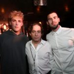 Three men posing together at a dimly lit party