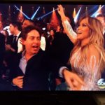 Man in an awards show audience with a performer nearby