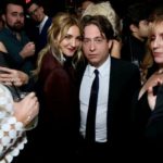 Man in a suit posing with friends at a dark party