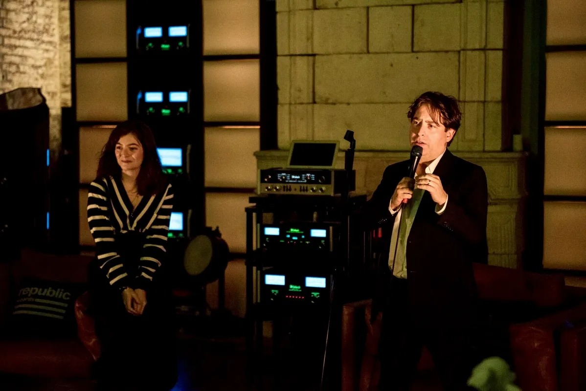 Man speaking into a microphone in a dim lounge