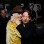 Man hugging a woman in a velvet jacket backstage