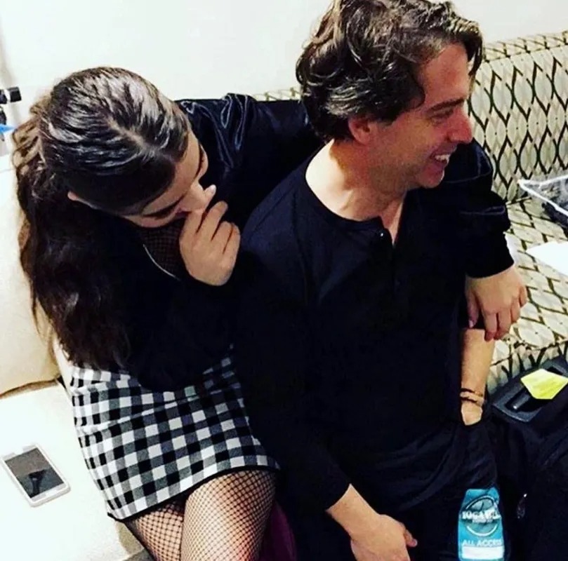 Man laughing with a woman seated beside him backstage