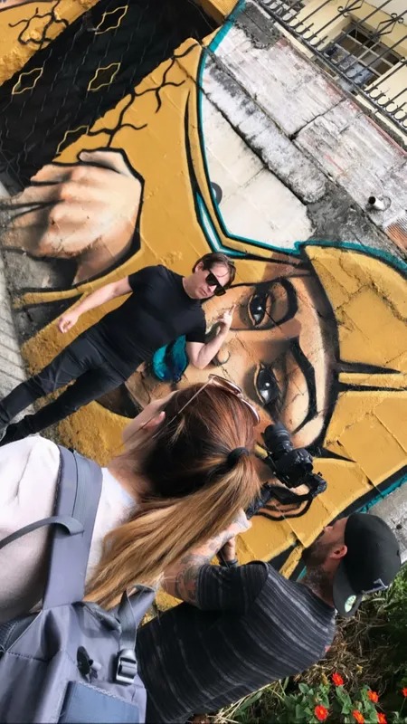 Selfie of a man in sunglasses in front of a street mural