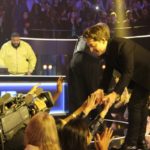 Man reaching down to fans from the edge of a stage