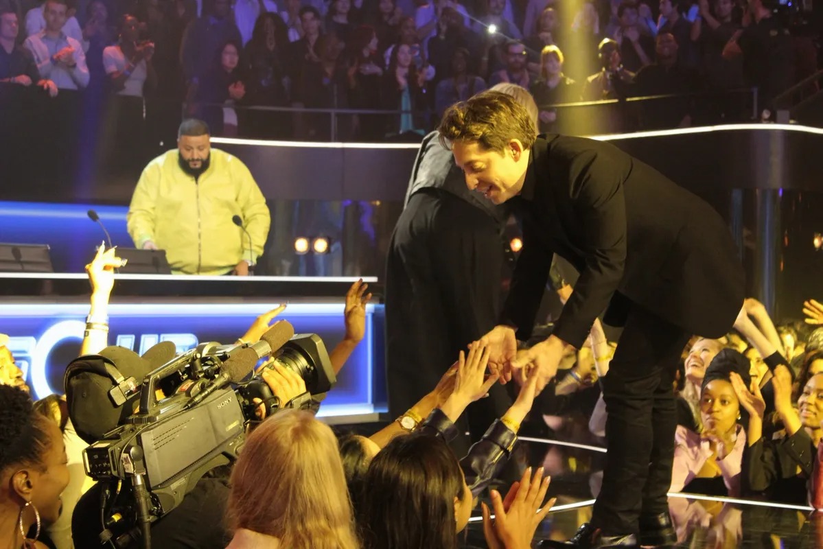 Man reaching down to fans from the edge of a stage