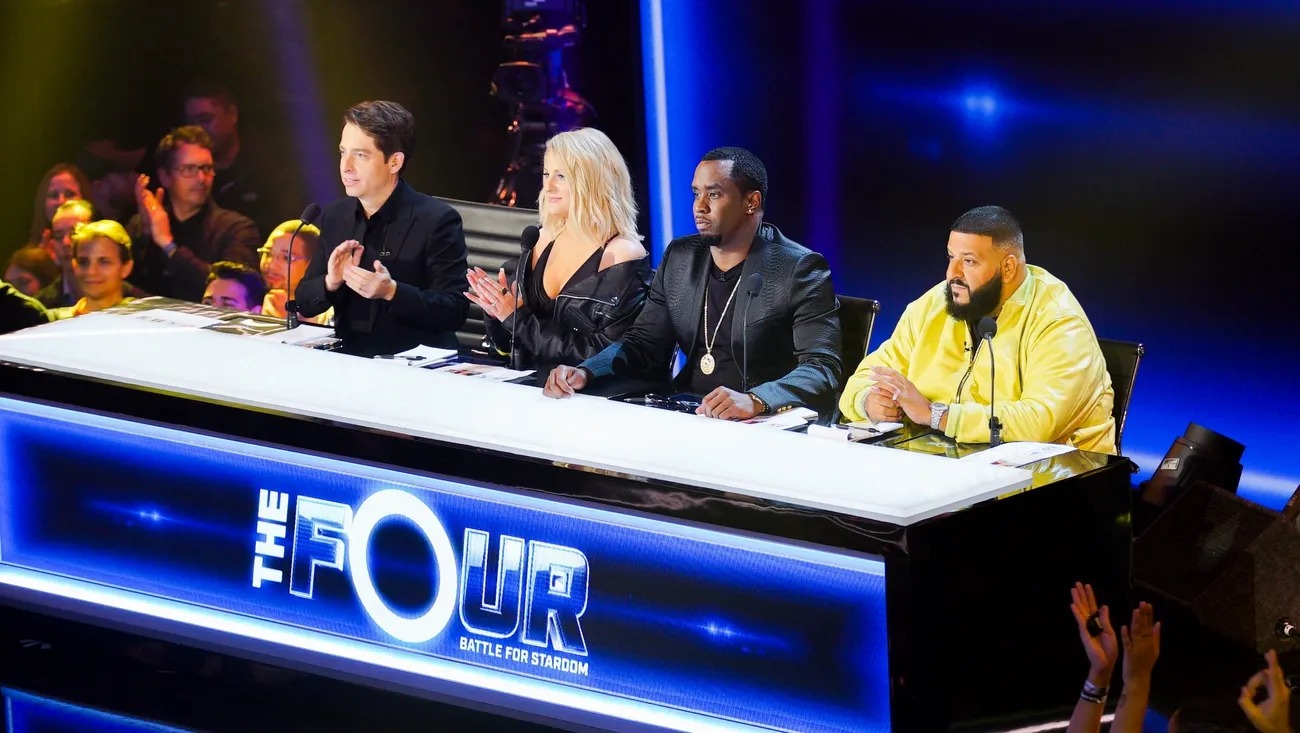 Four judges seated at The Four desk before a show