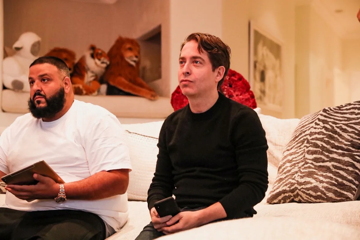 Two men sitting on a white sofa in a living room