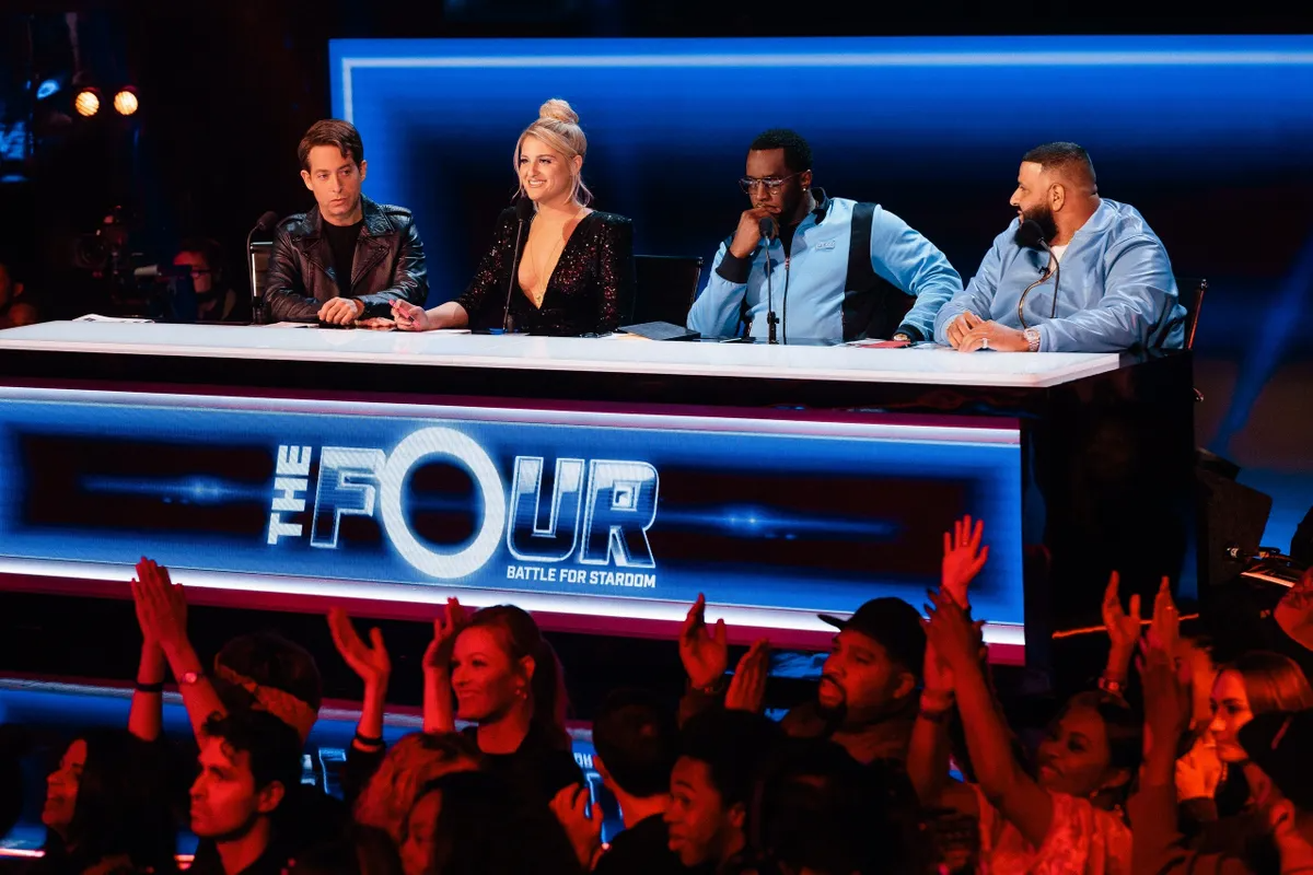 Judges seated at The Four television desk above the audience