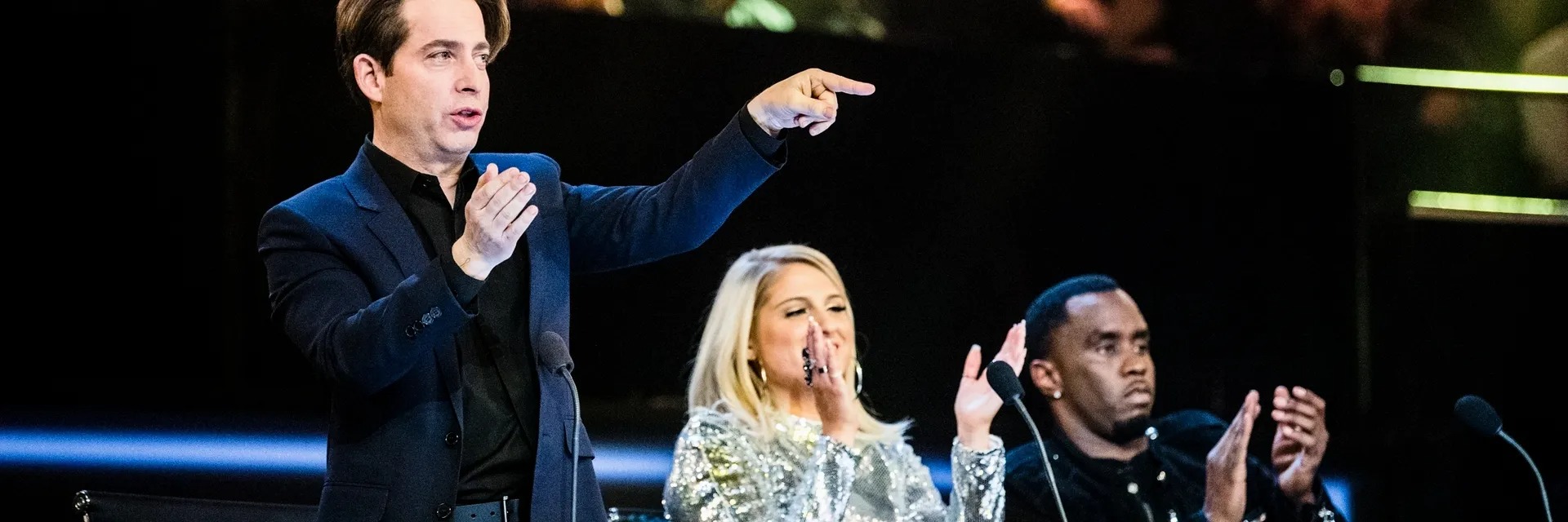 Man pointing from the stage as judges watch