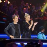 Two judges applauding at a glowing stage desk