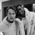 Black and white photo of two men smiling in hoodies
