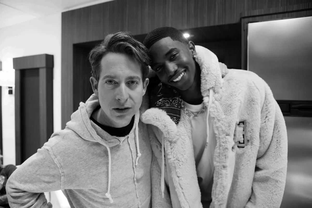 Black and white photo of two men smiling in hoodies