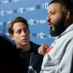 Two men talking face to face at a press event