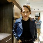 Man in a leather jacket standing in a backstage lounge