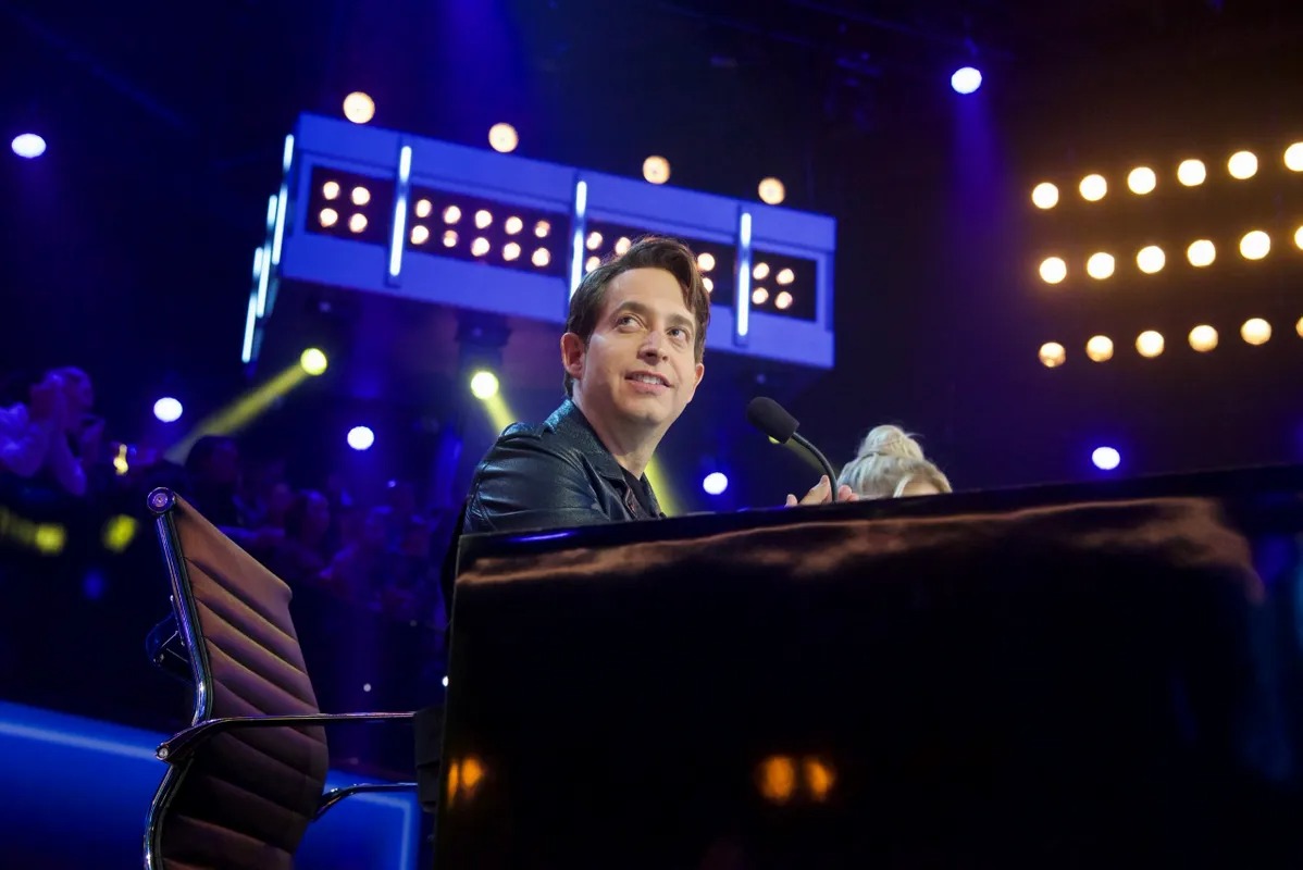 Man seated at a lit judges desk on a television set