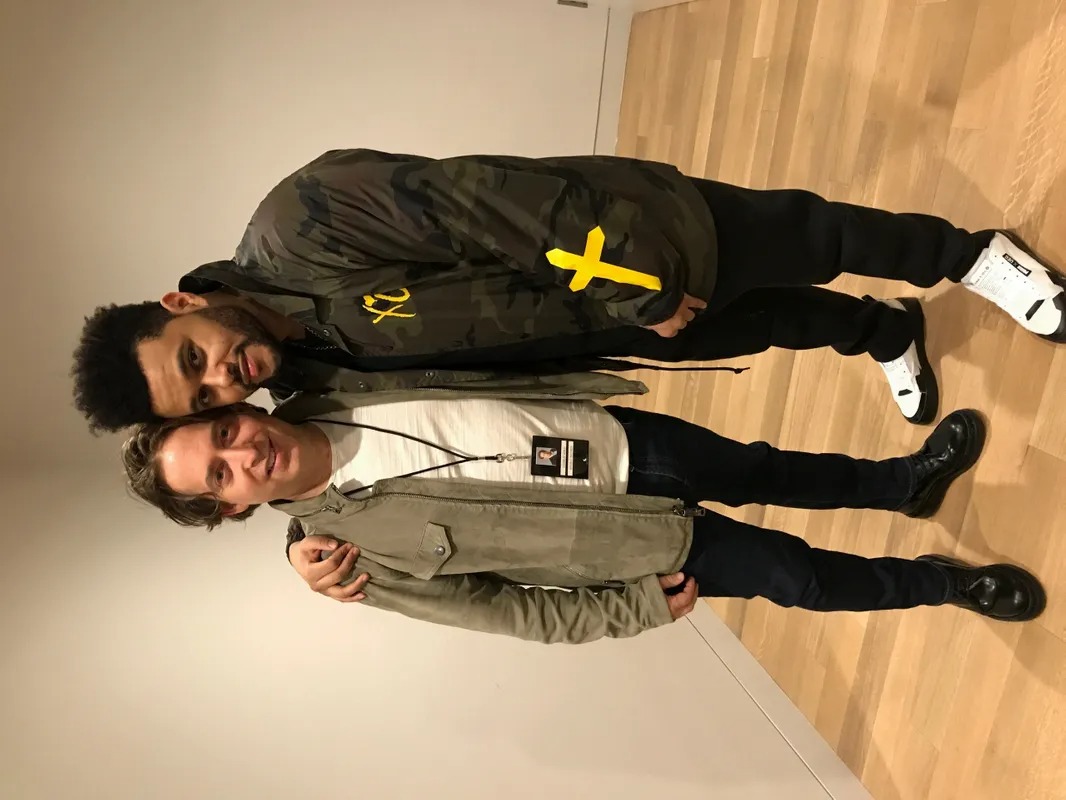 Two men lying on a wooden floor posing for the camera