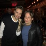 Two men posing together at a restaurant bar