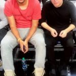 Two men seated side by side on a lounge sofa