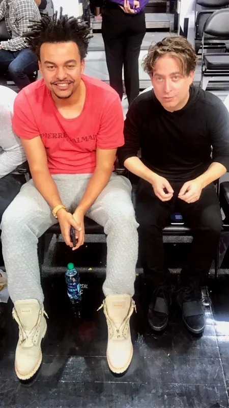 Two men seated side by side on a lounge sofa