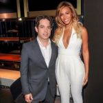 Man in a suit posing with a woman in a white jumpsuit