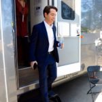 Man in a suit stepping out of a studio trailer