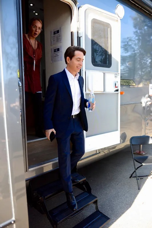 Man in a suit stepping out of a studio trailer