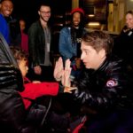 Man greeting fans in a crowded backstage area