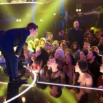 Man leaning over the stage edge toward the crowd