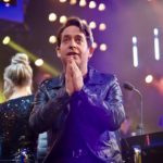 Man applauding on a brightly lit television stage