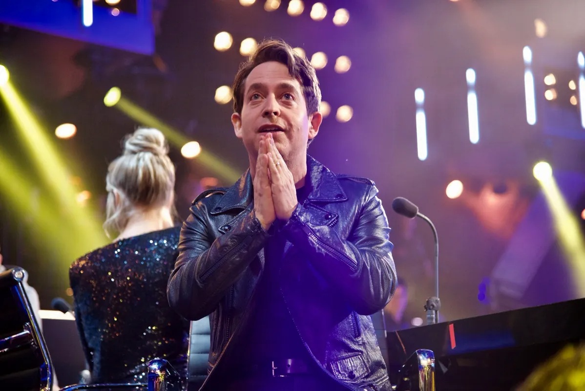 Man applauding on a brightly lit television stage