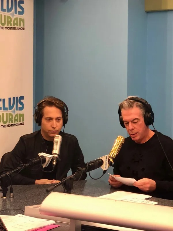 Two men in headphones recording a radio show