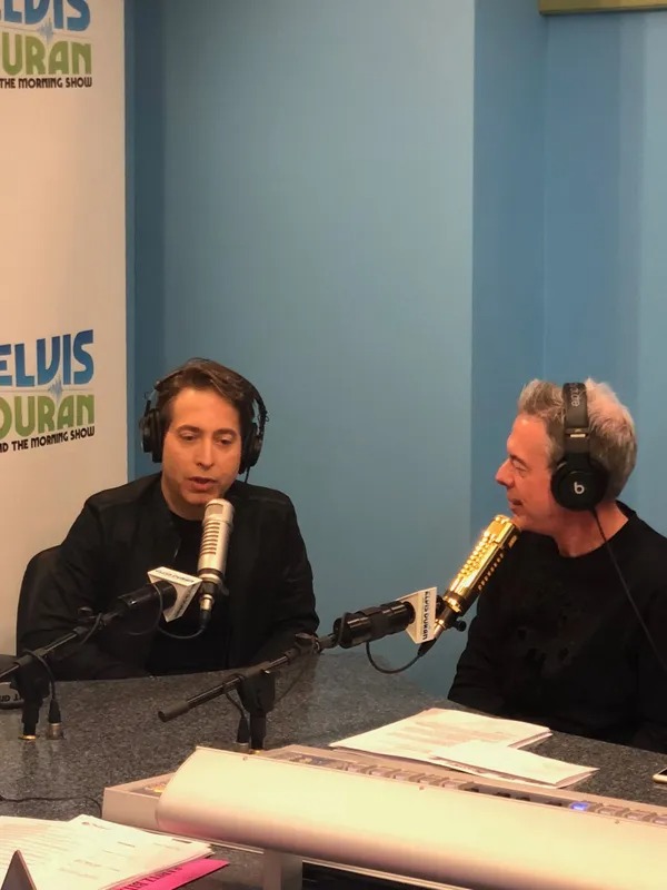 Radio host and guest talking into studio microphones