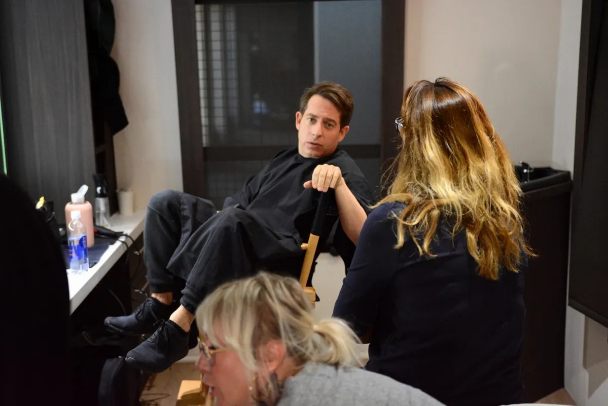 Man in a dressing room as a stylist prepares hair