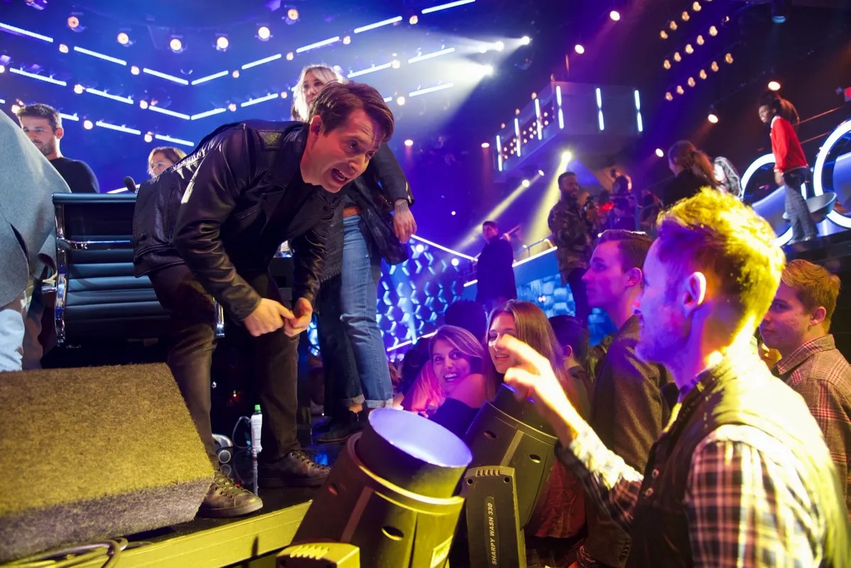 Performer leaning toward a cheering crowd at a live show