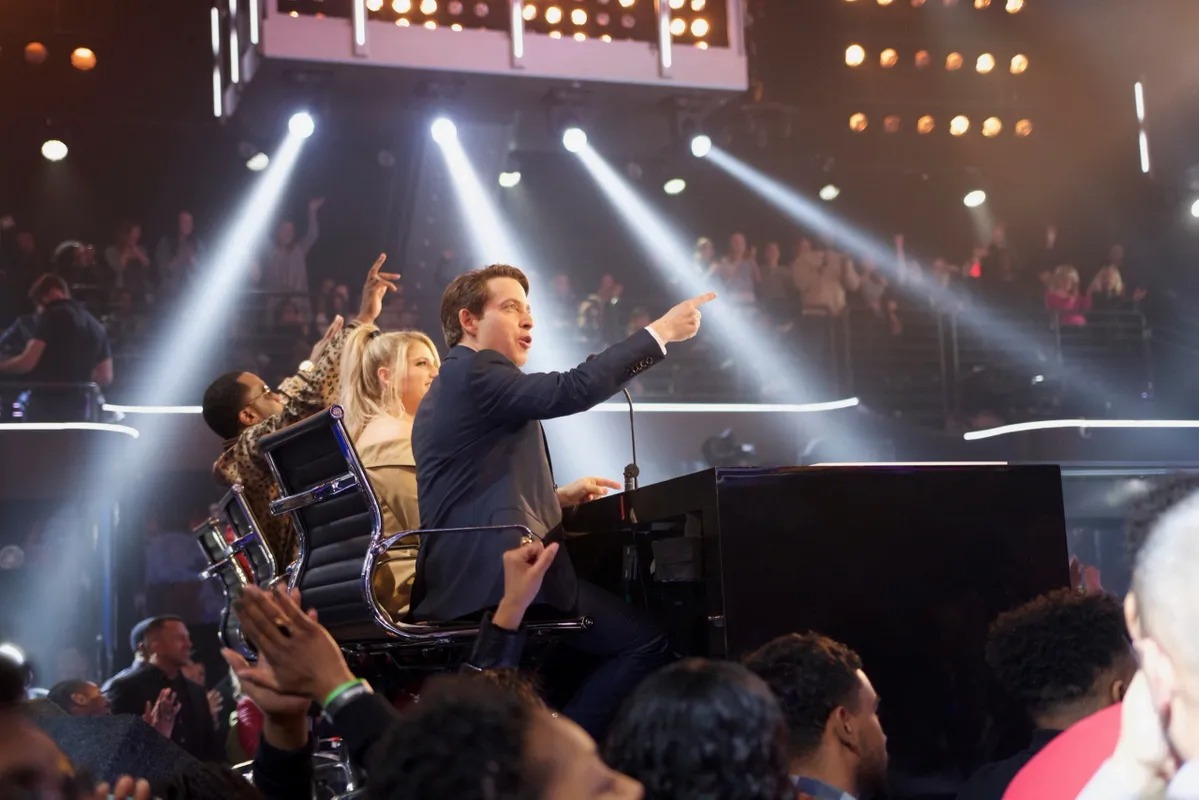 Man on stage pointing to the crowd under spotlights