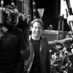 Black and white photo of a man smiling near a camera rig
