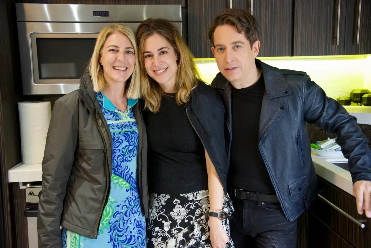 Three people posing together in a backstage kitchen