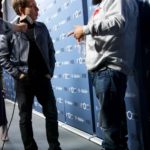 Two men being interviewed in front of a press backdrop