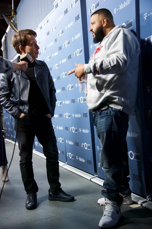 Two men being interviewed in front of a press backdrop