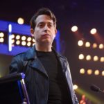 Man standing under rows of bright stage lights