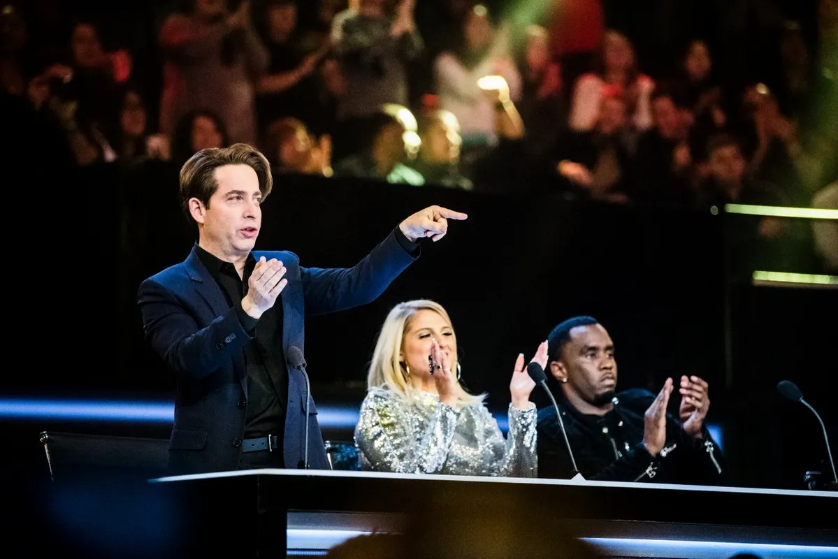 Judge pointing toward the stage from a lit desk
