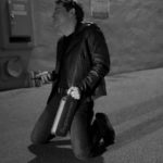 Black and white photo of a man kneeling in a hallway