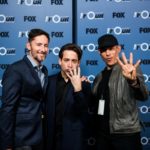 Three men posing together on a press wall