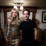Man and woman in a sequin dress posing in a trailer