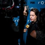 Man being interviewed by camera crews at a dark press line
